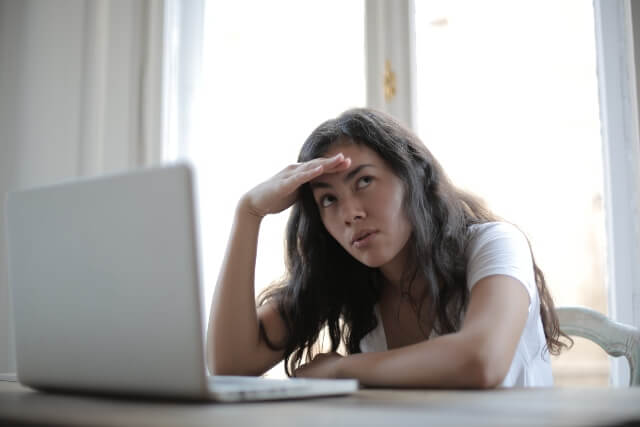 Woman sitting in front of a laptop with her head resting on her hand