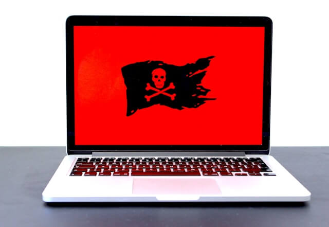 a computer with a red background and a black pirate flag