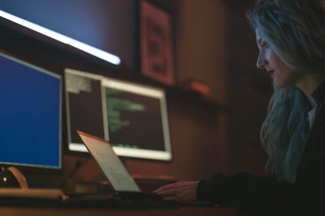 A Lady Working in front of 3 computers