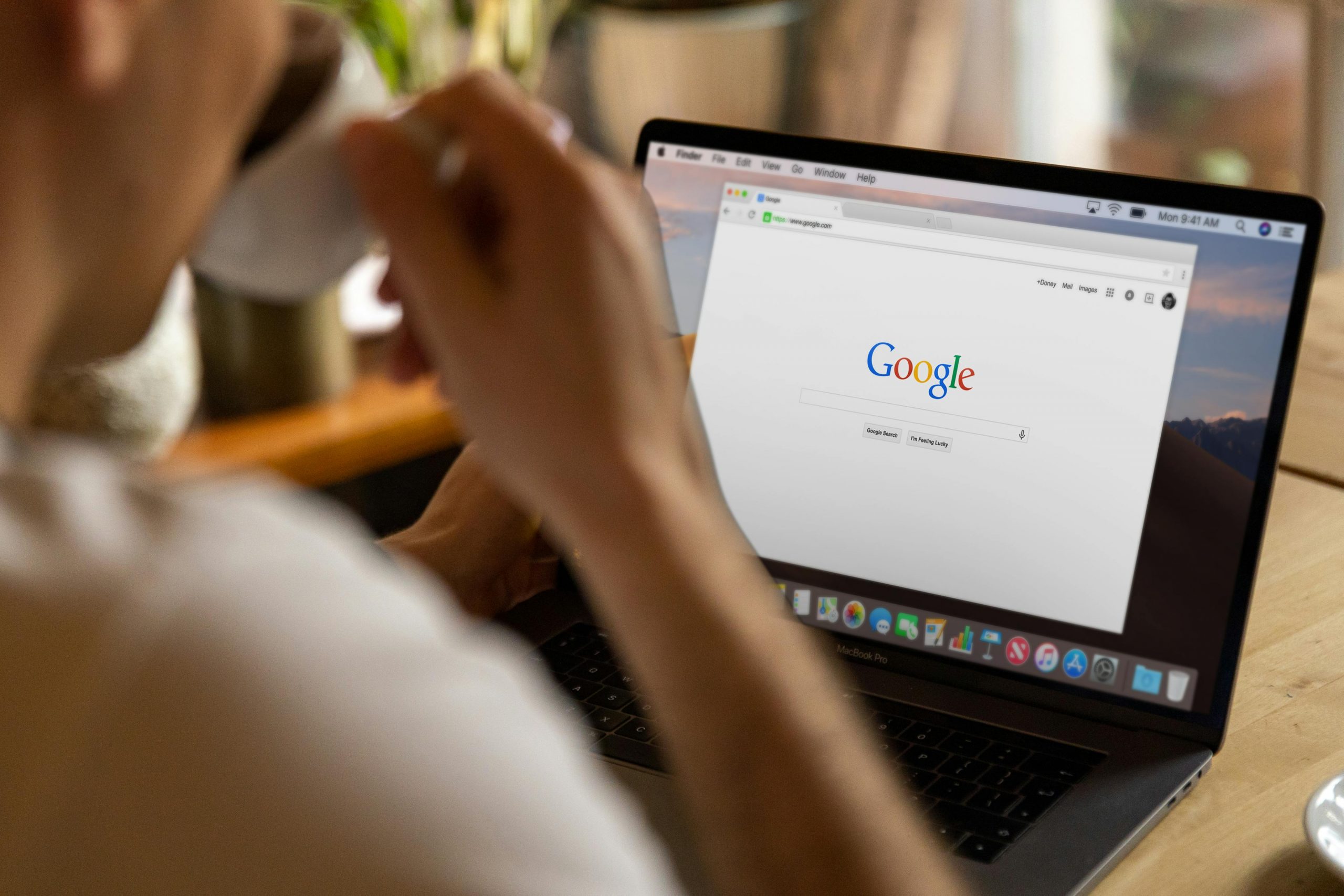 Man sitting in front of open laptop drinking coffee